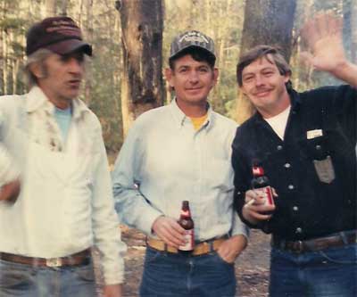 three men with beers in the woods