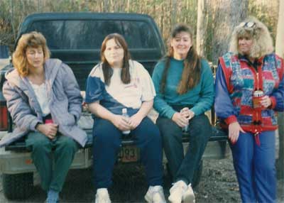 four women sit on a tailgate