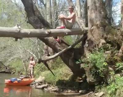 Brian sits on a tree over the river